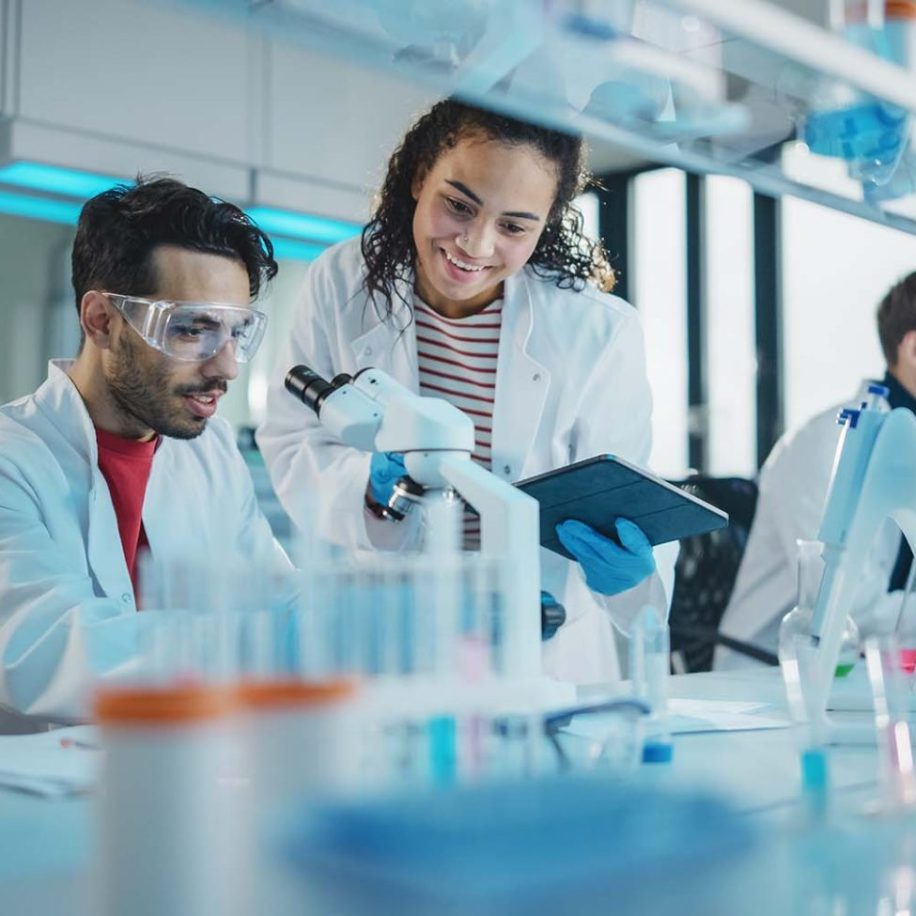Portrait-of-Latin-and-Black-Young-Scientists-Using-Microscope-Digital-Tablet-Doing-Sample-Analysis-Talking-aspect-ratio-1600-975